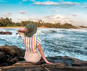 Young,Woman,In,Knitting,Hat,,Sitting,On,The,Ocean,Rocky